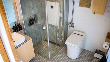 A bathroom with a glass-enclosed shower, a toilet, and a sink.
