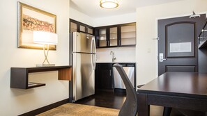 A compact kitchen with a refrigerator, stove, and microwave. There is a chair and a small table. A fire evacuation plan is posted on the door. - Residence Inn by Marriott Edmonton West (Edmonton)