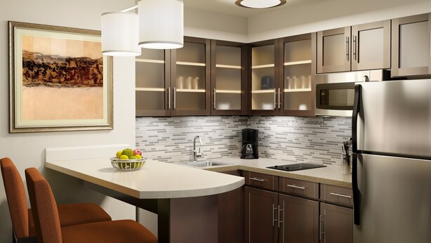 A modern kitchen with a central island, stainless steel appliances, and a backsplash of small tiles. - Staybridge Suites West Edmonton by IHG (Edmonton)