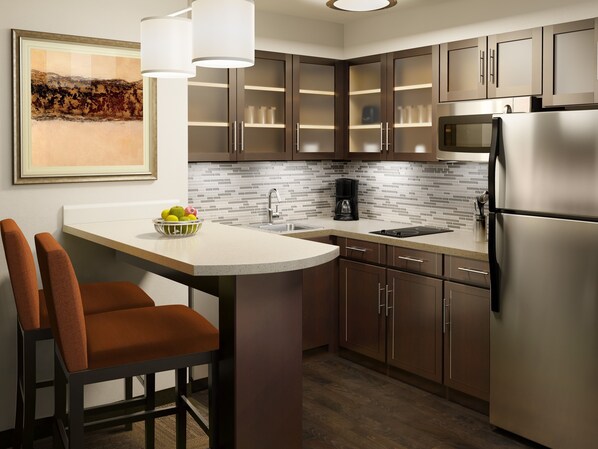 A modern kitchen with a central island, stainless steel appliances, and a backsplash of small tiles.