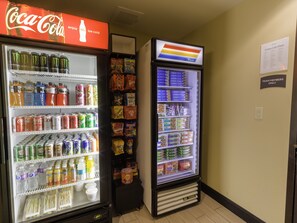 A vending machine stocked with snacks and beverages, including Coca-Cola and Monster energy drinks.