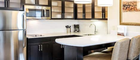 Una cocina moderna con electrodomésticos de acero inoxidable, microondas integrado y cafetera.