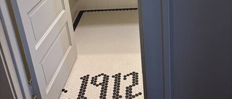 A bathroom with a white sink, a mirror above it, and a hexagonal patterned floor.