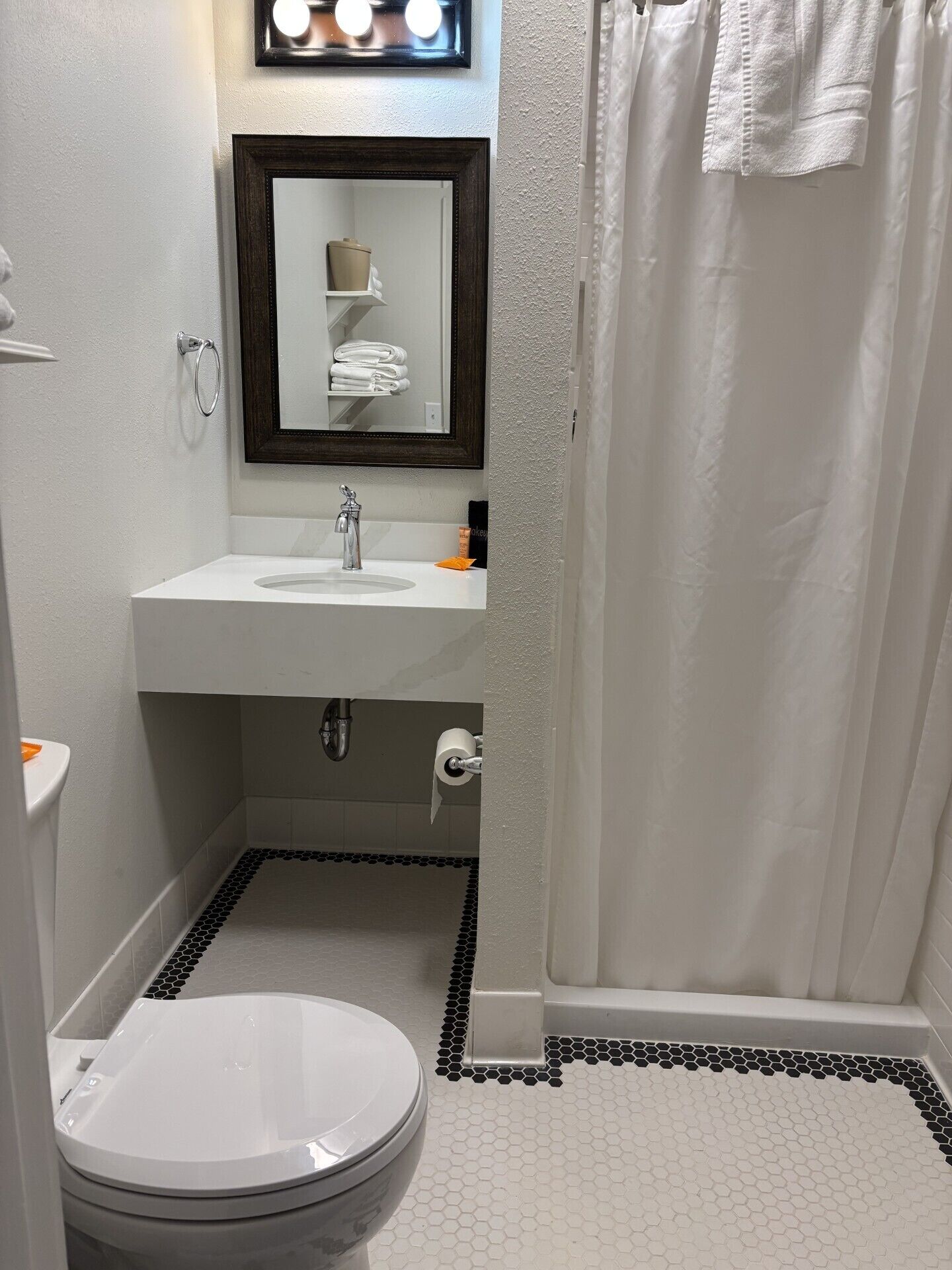 A bathroom with a toilet, sink, mirror, and shower curtain.