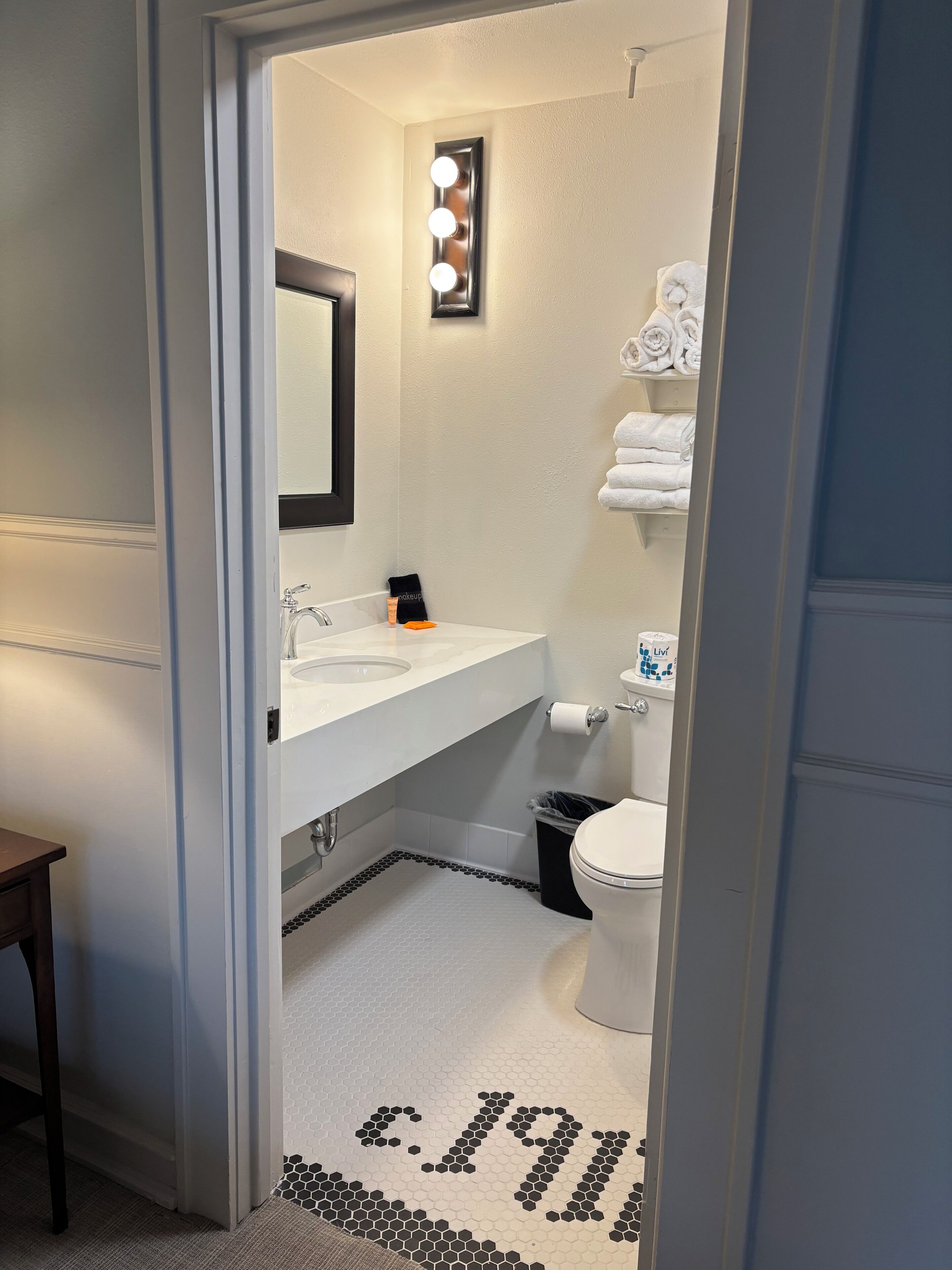 A bathroom with a white sink, a mirror, a toilet, and a towel rack.