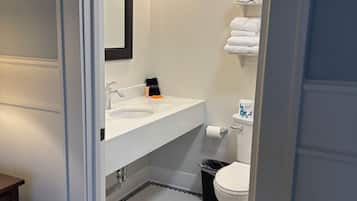 A bathroom with a white sink, a mirror, a toilet, and a towel rack.