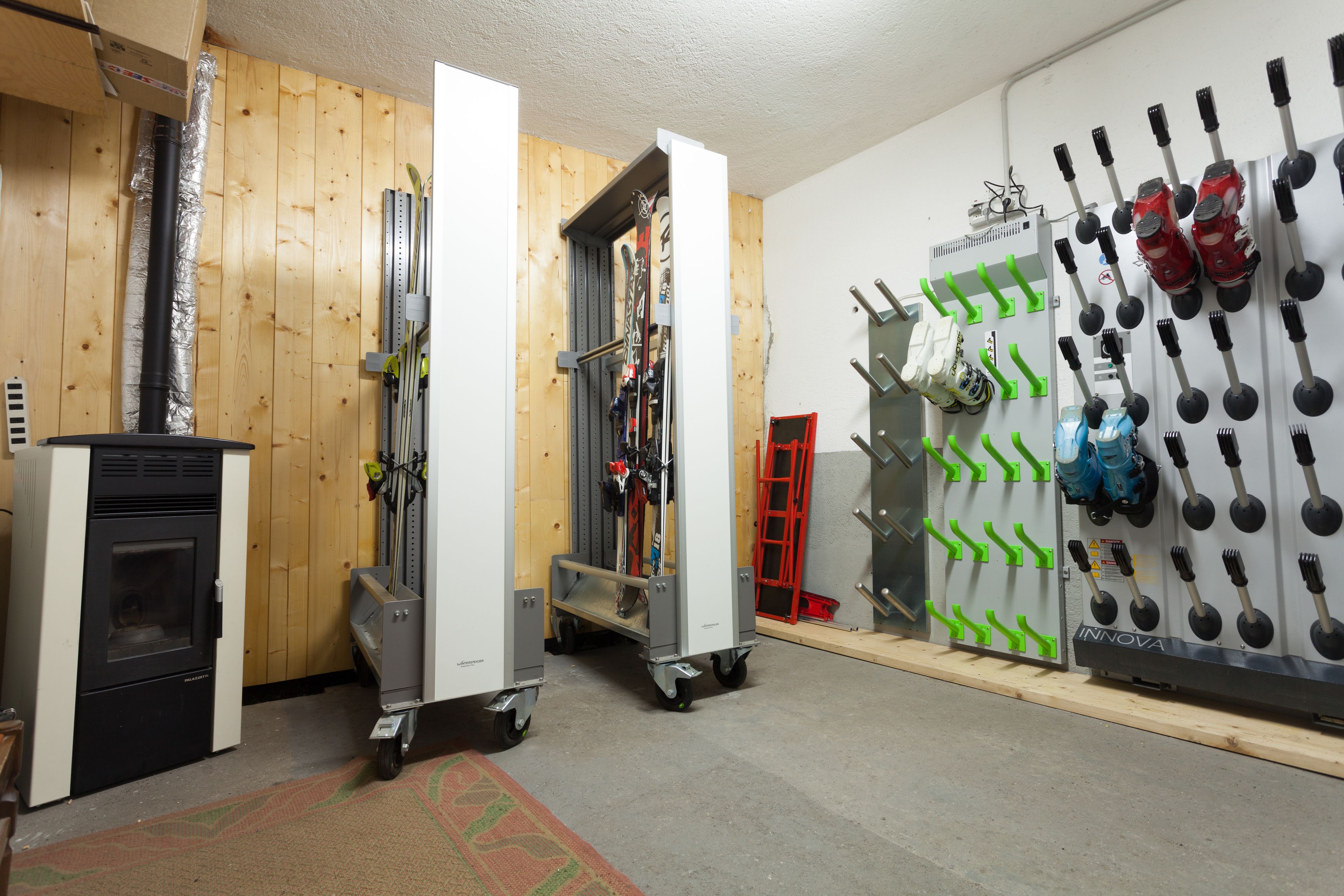 A ski storage room with racks for skis and ski boots, a ski lift, and a fireplace.