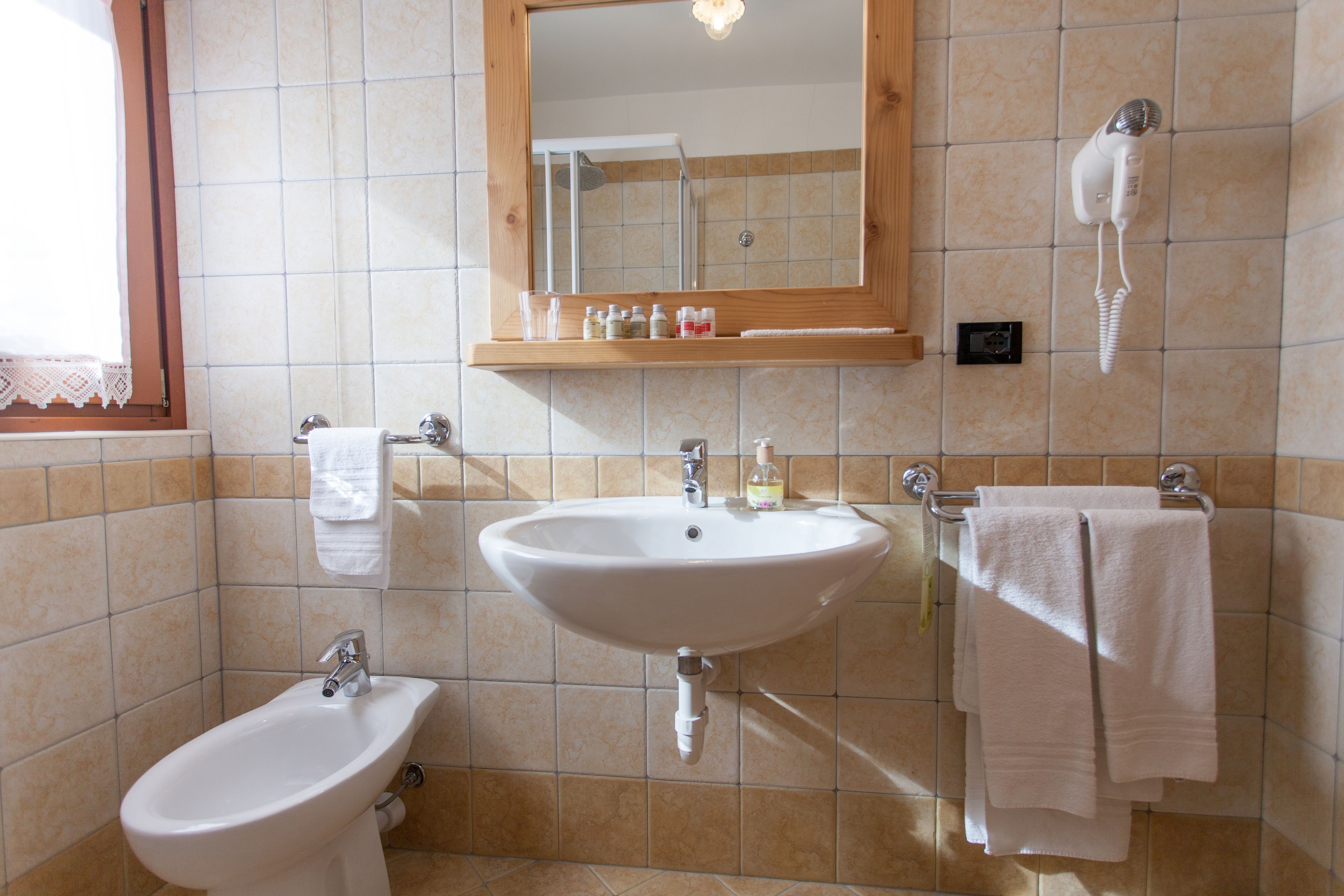 A bathroom with a sink, bidet, and a hairdryer mounted on the wall.
