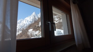 Una ventana con vistas a montañas nevadas y un cielo despejado.