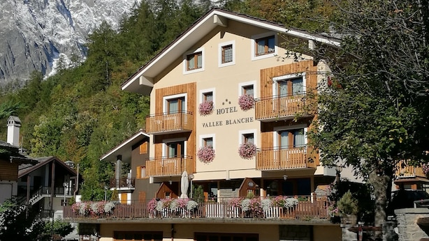 Un hotel con balcón, fachada de madera y un letrero que dice 'Hotel Vallye Blanche'.