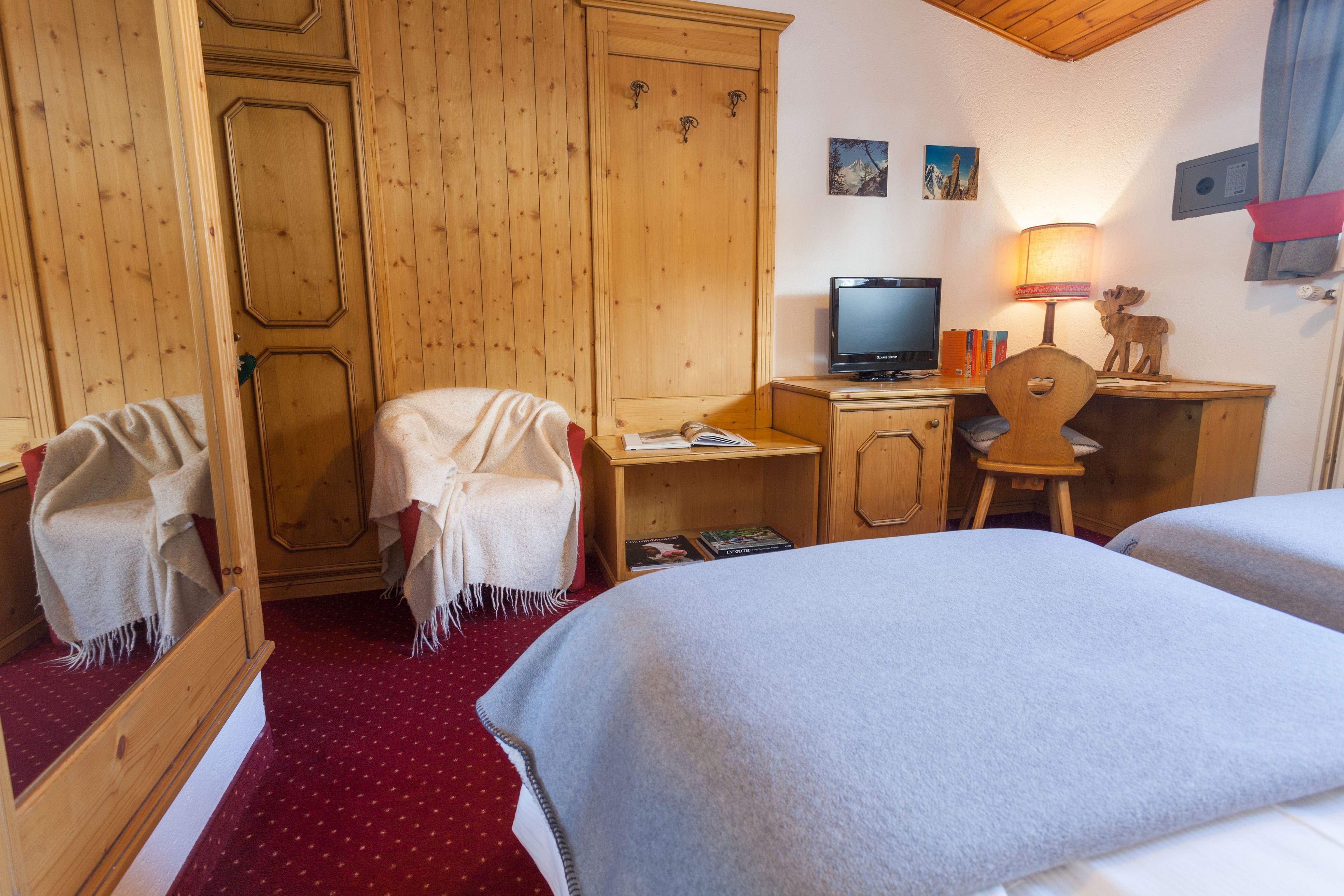 A hotel room with two beds, a desk with a computer, a chair, and a wardrobe.