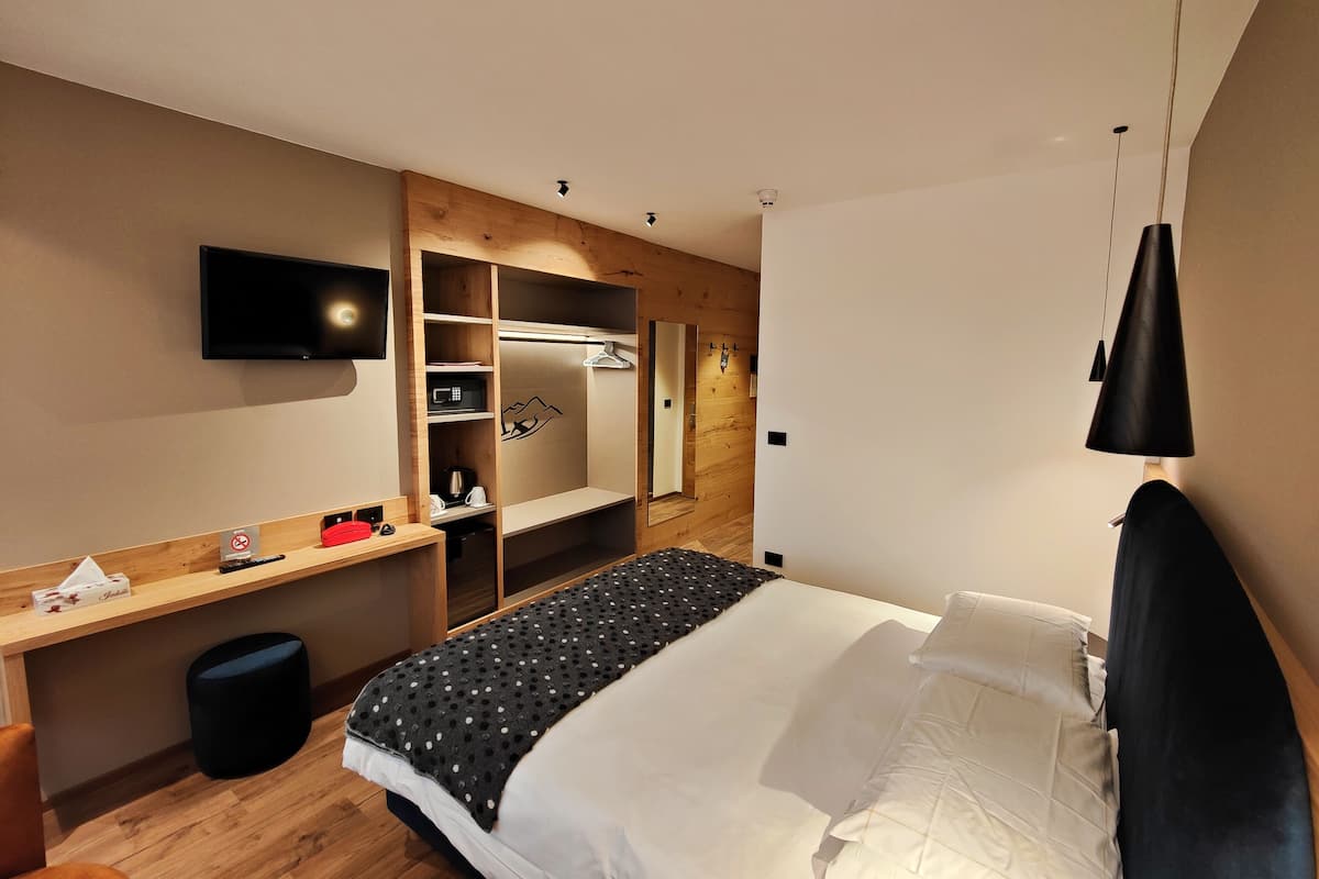 Une chambre d’hôtel équipée d’un lit, d’un bureau, d’une télévision et d’une armoire.