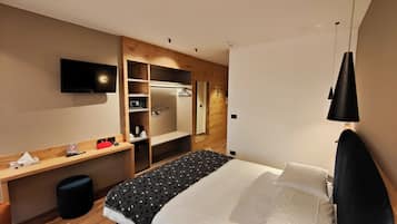 A hotel room with a bed, a desk, a TV, and a wardrobe.