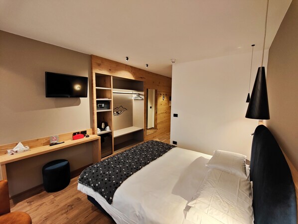 Una habitación de hotel con cama, escritorio, televisor y armario.