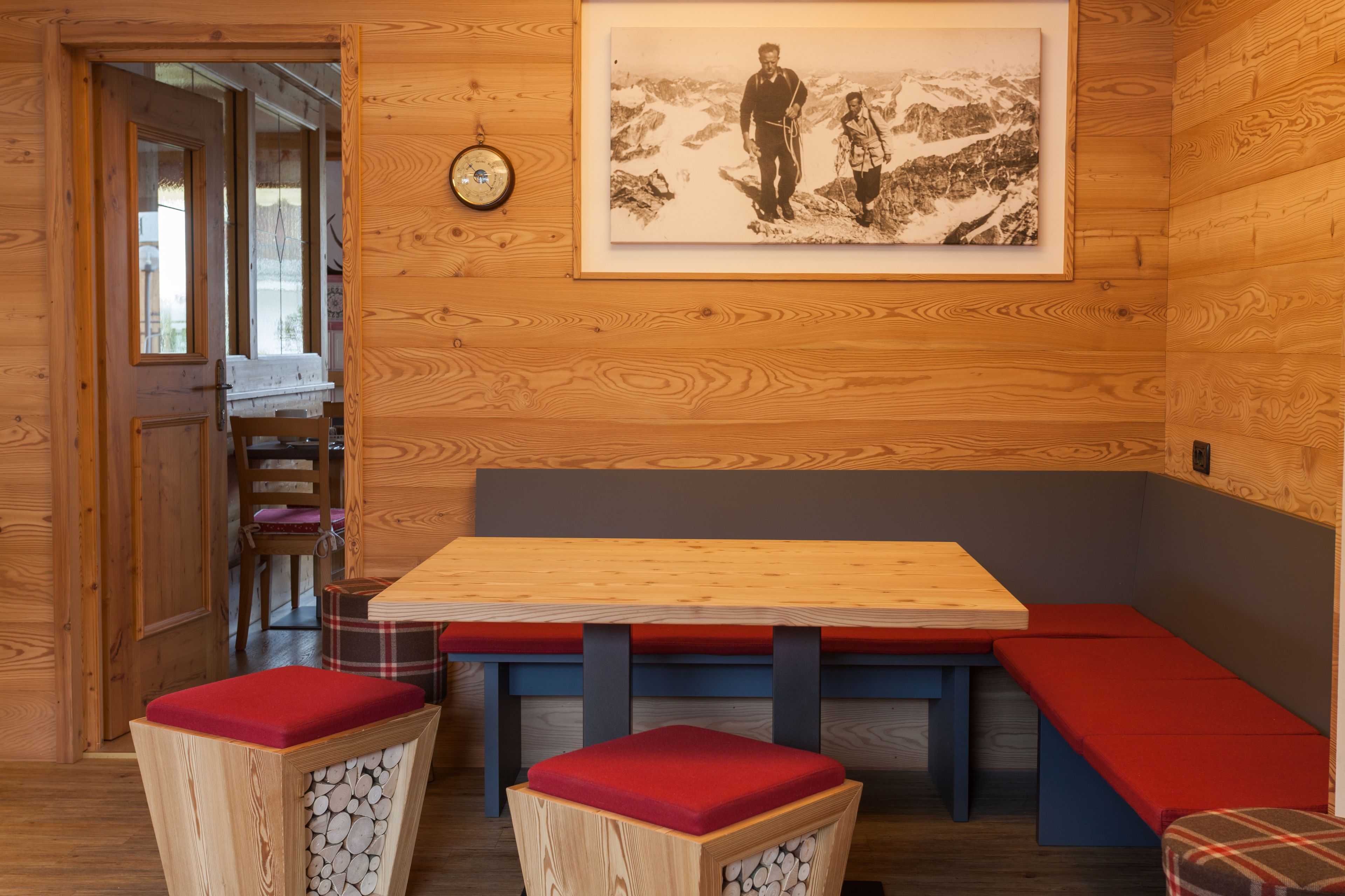 A wooden interior with a bench seating area, a table, and a framed photograph on the wall.