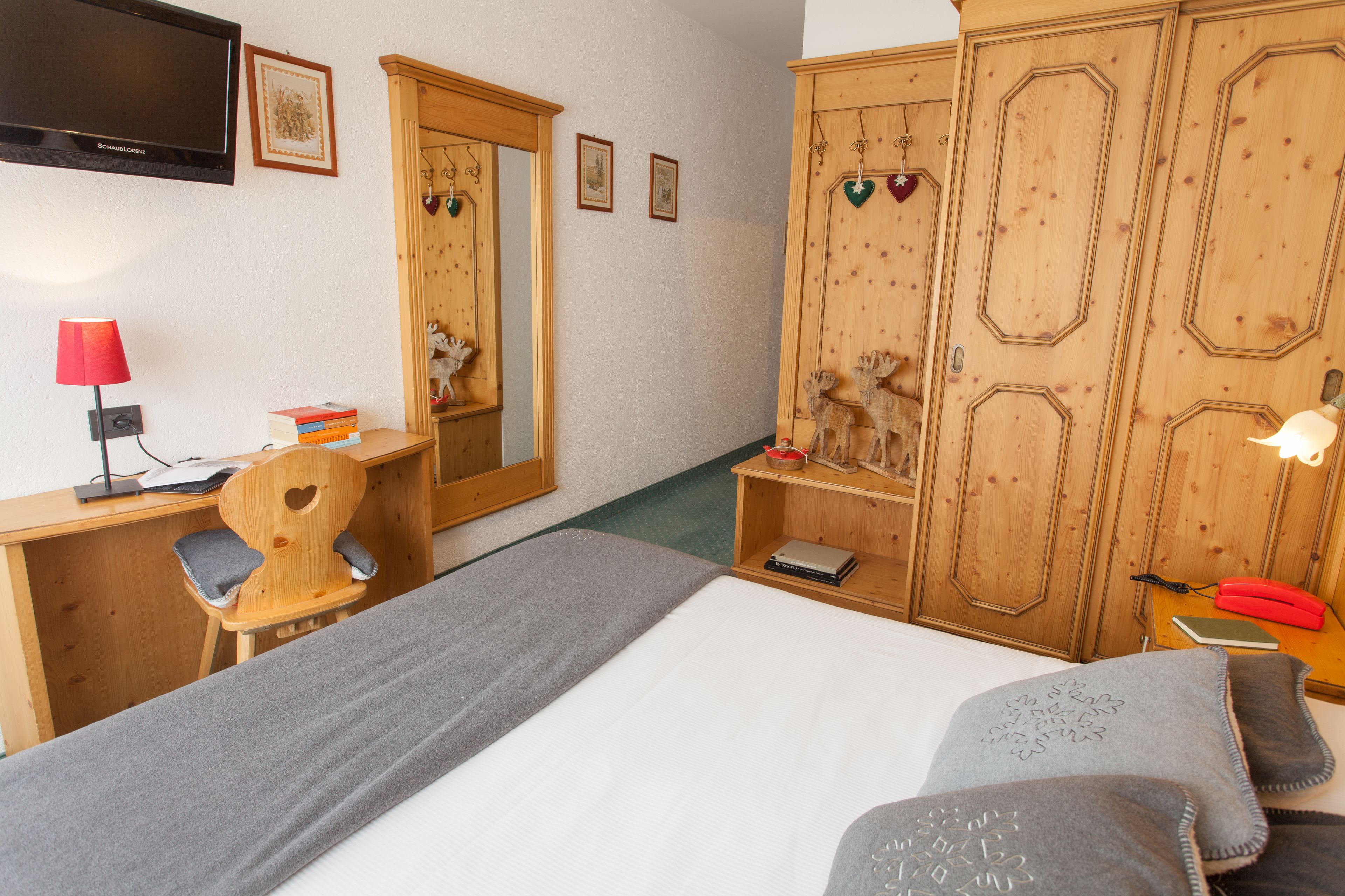 Un dormitorio con cama, un escritorio con silla, televisor y armarios de madera.