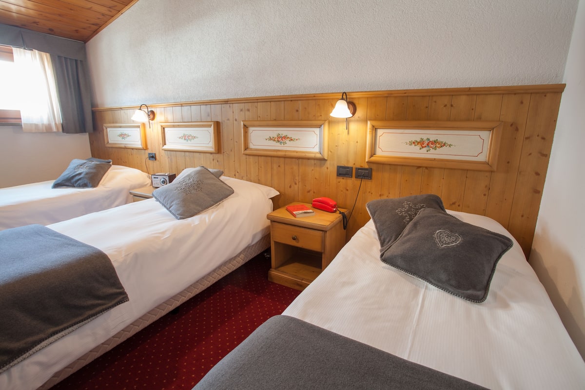 Une chambre d’hôtel avec deux lits, des têtes de lit en bois et des décorations florales encadrées.