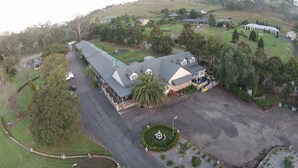 An aerial view of a large estate with multiple buildings, a central parking area, and surrounding greenery. - Picton Valley Motel (Picton)