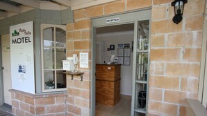 A brick exterior of a motel with a reception desk and a sign indicating the name. - Picton Valley Motel (Picton)