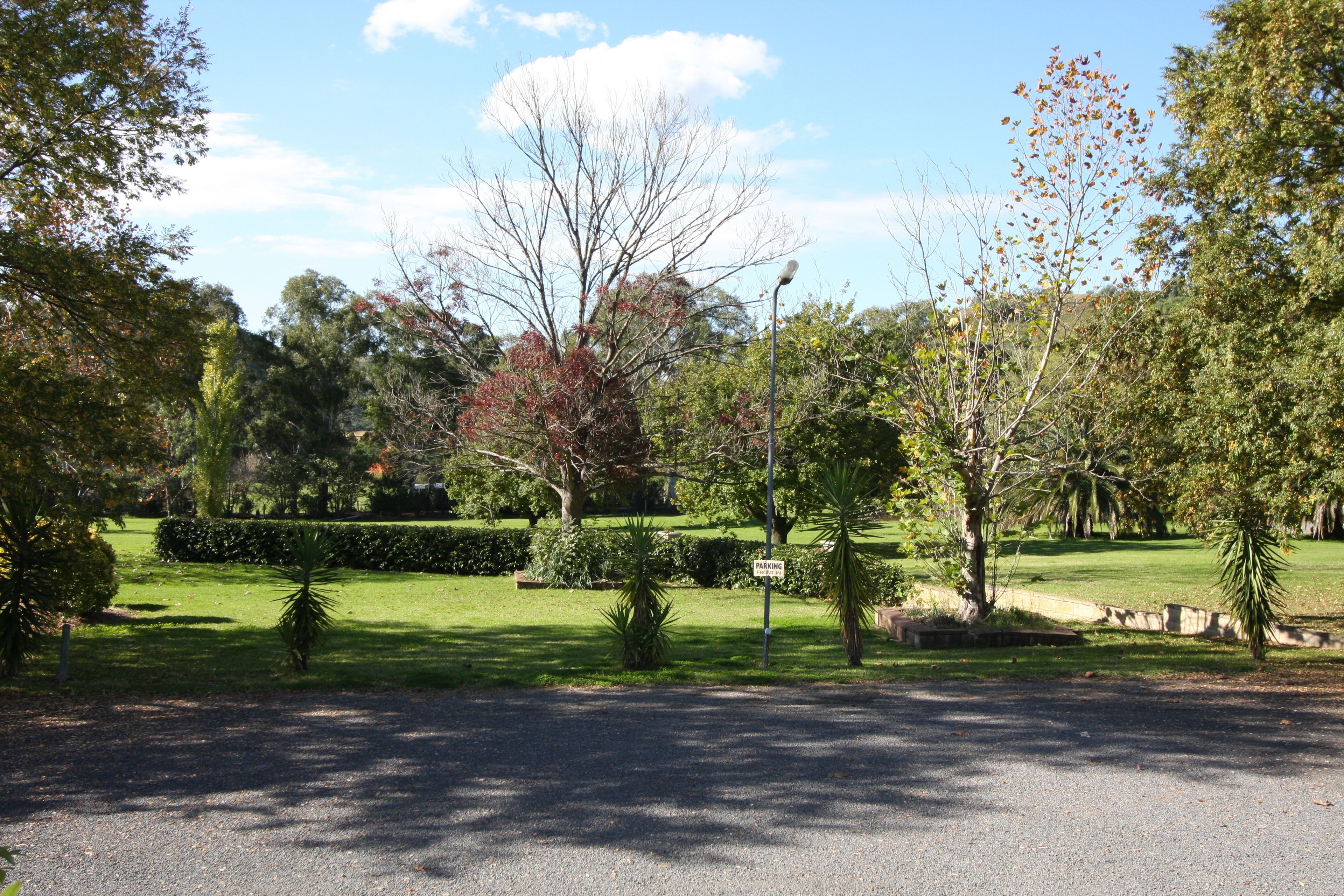 A paved driveway leading to a parking area with a sign indicating parking availability.