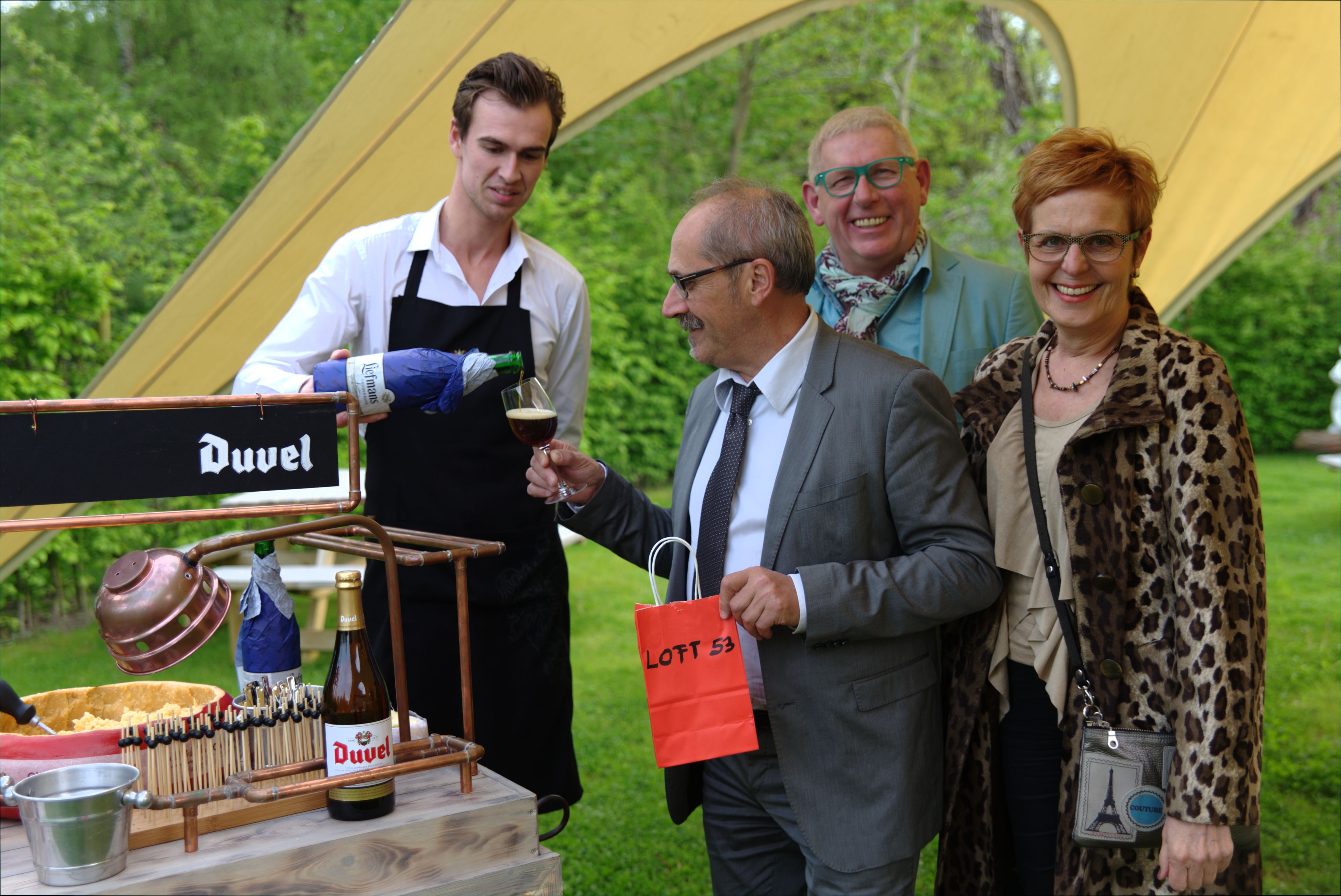 A beer tap station with a Duvel beer bottle, a copper tap, and a wooden barrel.