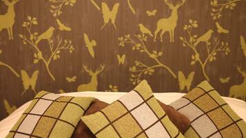 Una cama con dos almohadas y una pared con papel tapiz de temática natural.