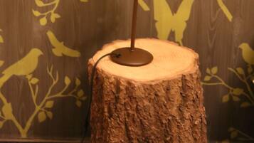Une lampe posée sur un tronc d’arbre dans une pièce dont un mur est décoré de silhouettes d’animaux sauvages.