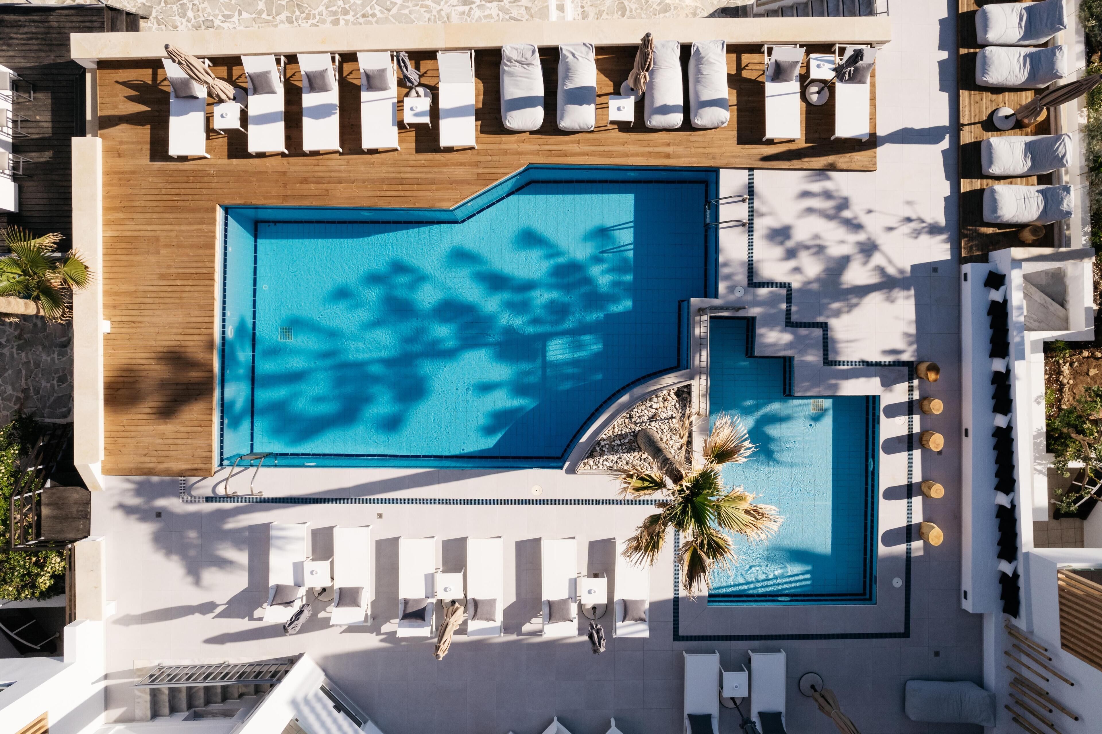 Vue aérienne d’un hôtel doté d’une grande piscine, de transats et d’une terrasse en bois.