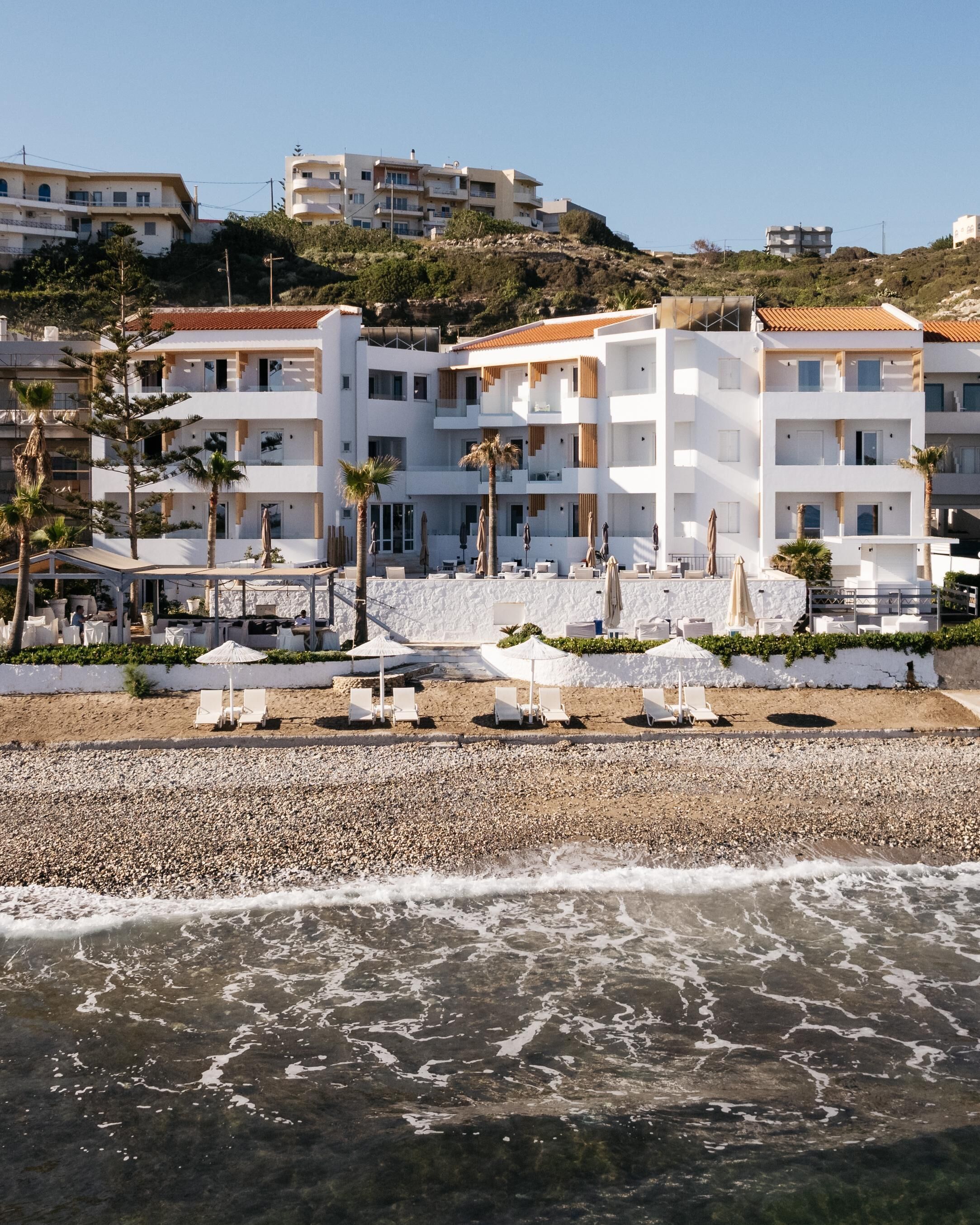 A beachfront hotel with multiple balconies, a pebble beach, and a view of the sea.