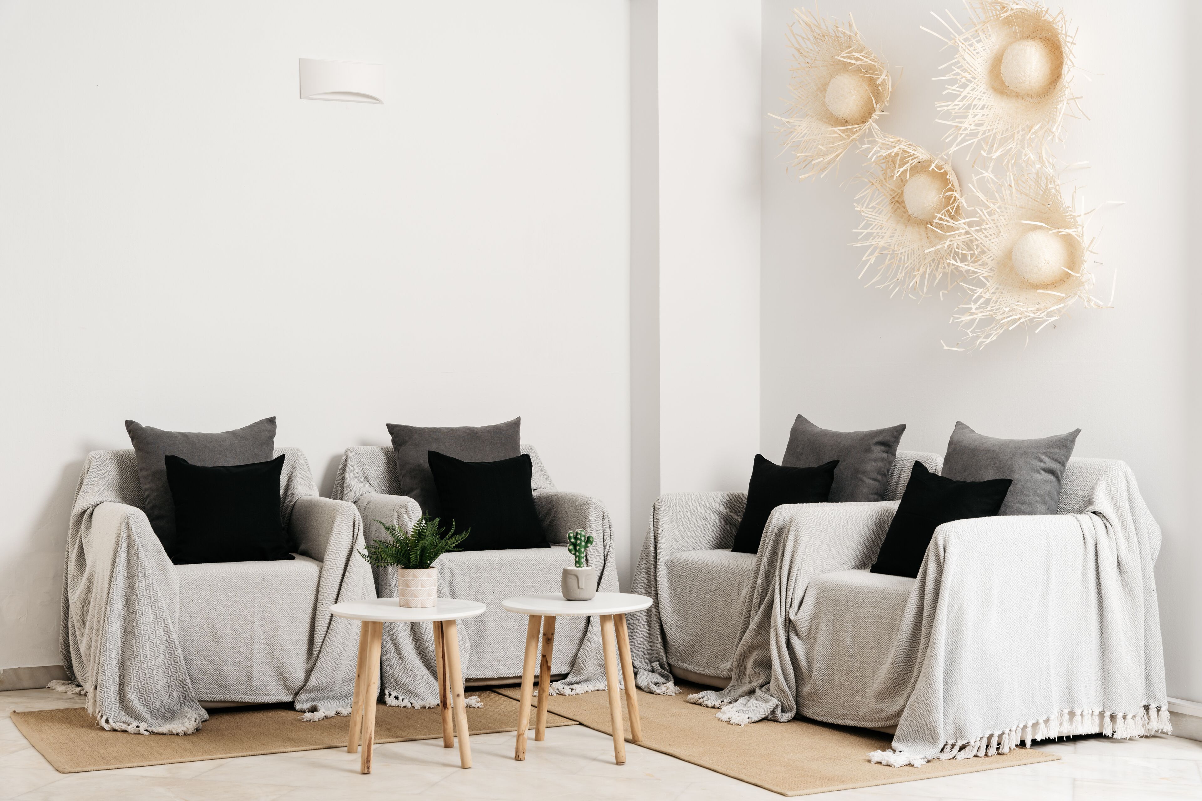 A modern living room with two grey sofas, black cushions, a small round table, and a decorative wall piece.