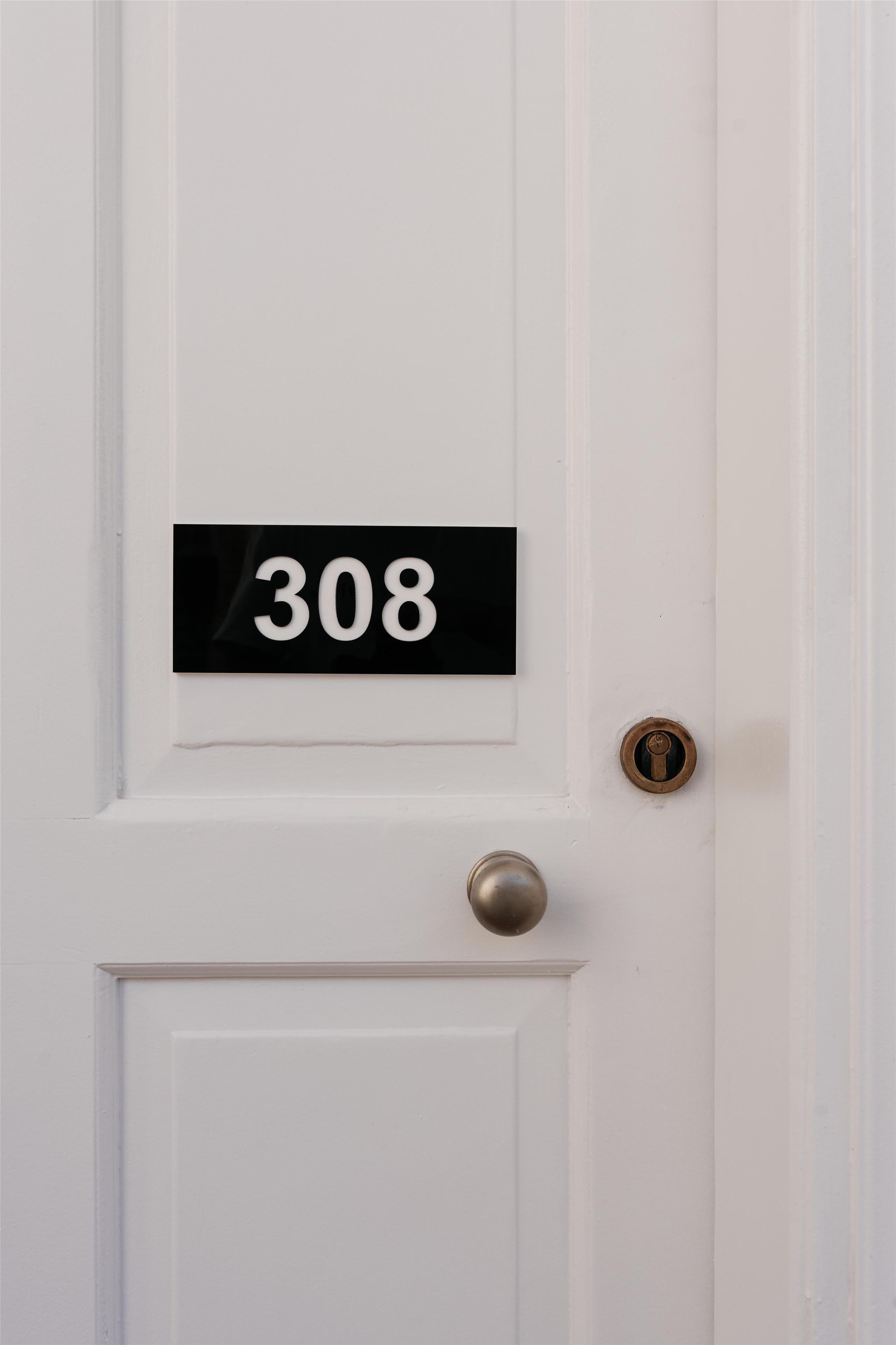 A white door with a black number plate displaying "308".