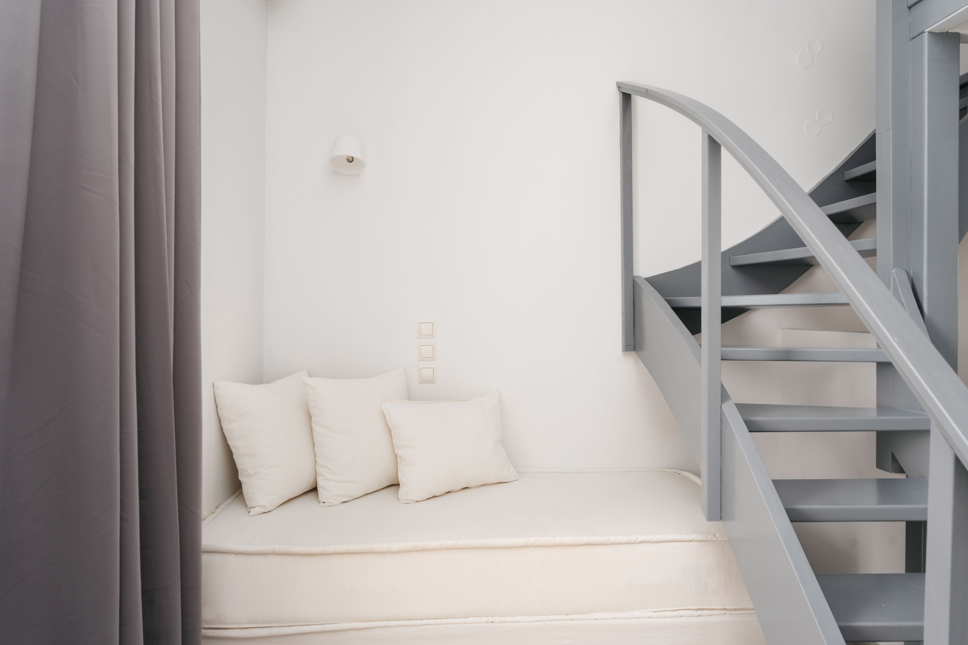 A modern room with a white sofa, a grey spiral staircase, and a minimalist design.