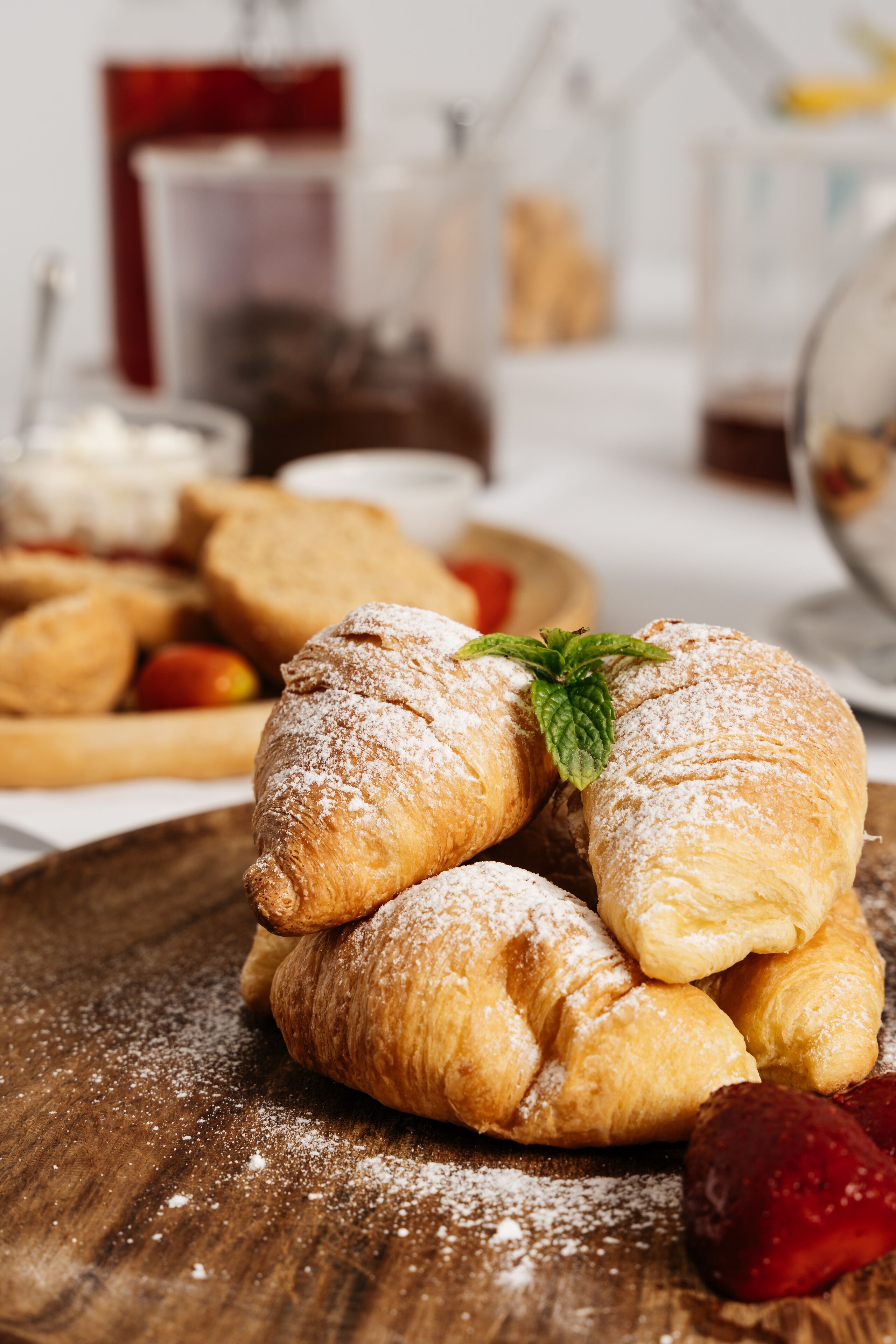 A wooden table with pastries, including croissants and a strawberry.