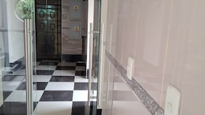 A hotel lobby with a checkered floor, a glass partition, and a door with a keycard lock. - Hostal Jovita (Santiago de Surco)