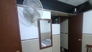 A room with a bed, a mirror, a fan, and a door. - Hostal Jovita (Santiago de Surco)