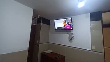 Une salle de bain avec un téléviseur fixé au mur, sur lequel on peut voir une personne.