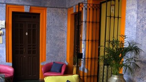 Una habitación con un sofá de madera, una mesita con un florero y una planta en maceta.