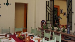 Un comedor con una araña, sillas de madera y una mesa dispuesta para una comida.