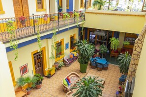 A courtyard with a seating area, potted plants, and a balcony with railings. - Casa VilaSanta - Hostel (Guadalajara)