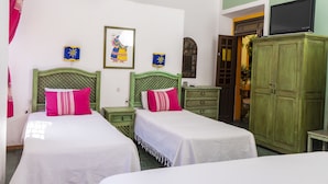 Una habitación con dos camas, un armario verde, un televisor y un cuadro en la pared.