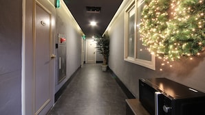A hallway with a Christmas wreath, a potted plant, and a fire alarm. - BSB Hotel (Busan)