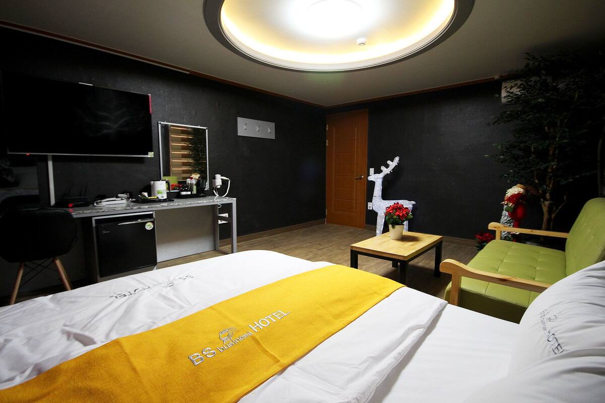 Habitación de hotel con cama, escritorio, silla y una mesita con una planta.