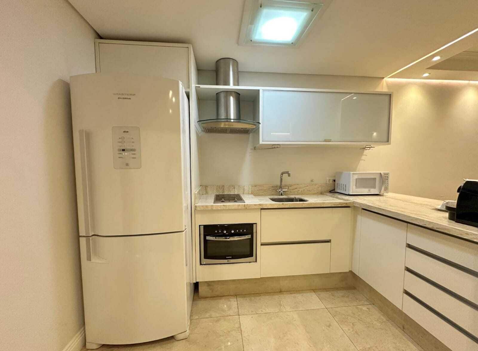A compact kitchen with a refrigerator, oven, microwave, and a sink.
