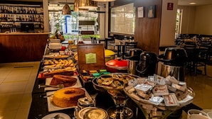 A buffet area with various food items and a bar with bottles in the background. - Travel Inn Flats Jardins (São Paulo)