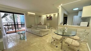 A modern living room with a glass dining table, a sofa, and a balcony with a view of buildings. - Travel Inn Flats Jardins (São Paulo)