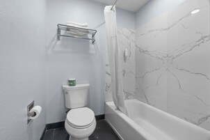 Un baño con inodoro, toallero, cortina de ducha y bañera.
