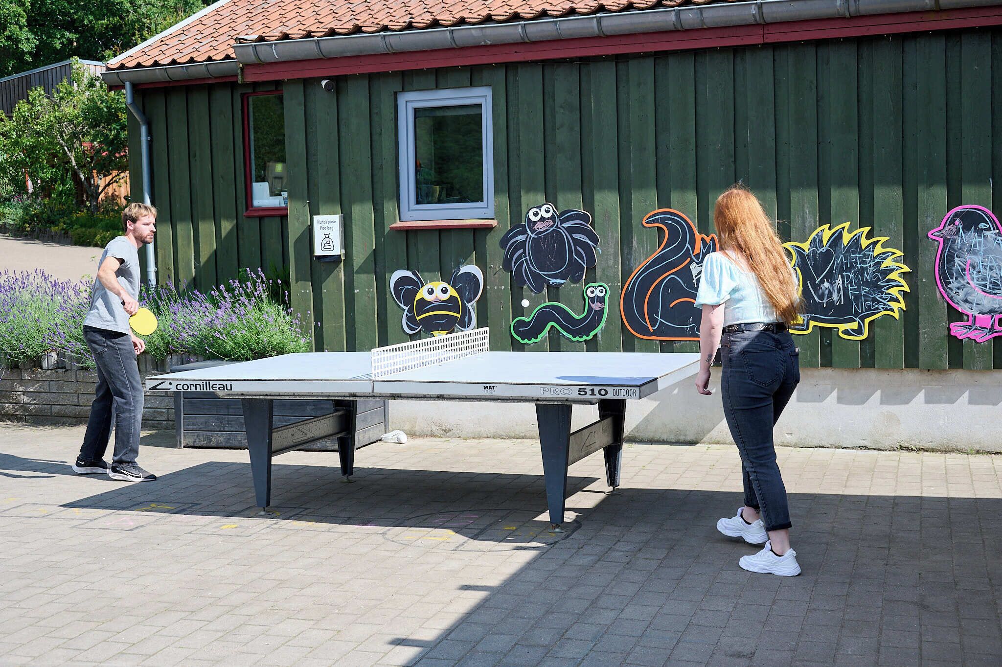Una mesa de ping-pong al aire libre, con grafitis en la pared de fondo.