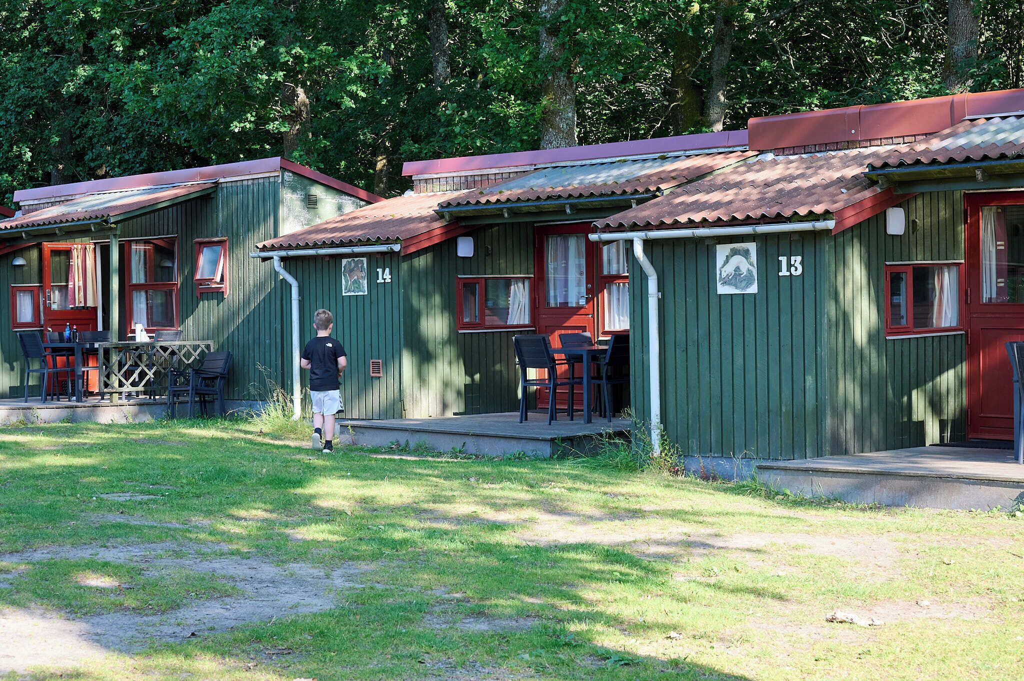 A row of cabins with numbered doors, a grassy area in front, and a person standing by one of the cabins.