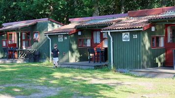 A row of cabins with numbered doors, a grassy area in front, and a person standing by one of the cabins.