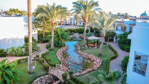 A resort with a swimming pool, palm trees, and a bridge. - Dive Inn Resort (Sharm El Sheikh)